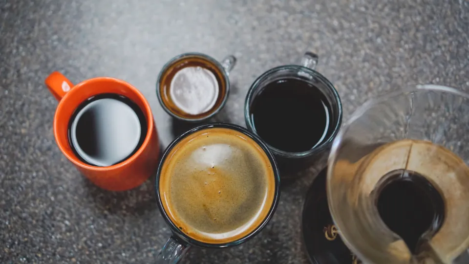 Varias tazas de café sobre una mesa oscura, vistas desde arriba.