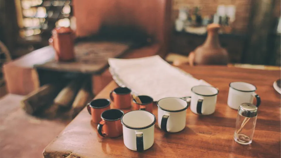 Varias tazas y un reloj de arena sobre una mesa de madera.