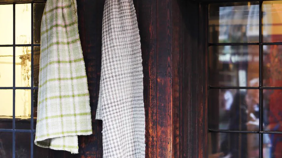 Toallas y ropa blanca colgadas de forma ordenada en una pared de madera.